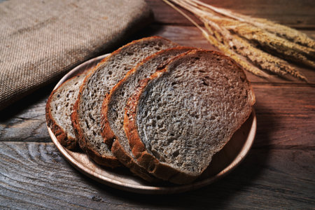bread loaf and wheat ears and sack on wooden background.の写真素材