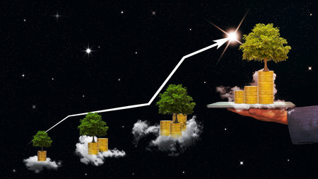 Businessman holding a tablet with piles of coins and tree and cloud on black sky background,business growth and chart of indicators conceptの写真素材