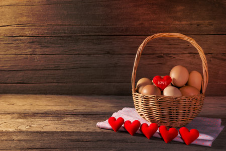 eggs in a wicker basket with heart-shaped on wooden tableの写真素材