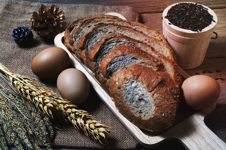 bread loaf and wheat ears and sack on wooden background.の写真素材