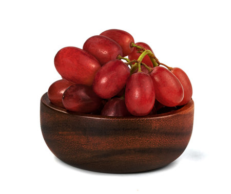Closeup red seedless grapes with wooden bowl isolated on white backgroundの写真素材
