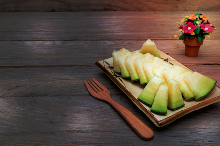 melon sliced on dish with wooden forkon wooden tableの写真素材