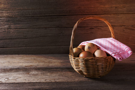 eggs in a wicker basket on wooden tableの写真素材