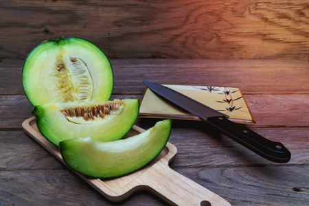 green melon and knife on wooden trayの写真素材