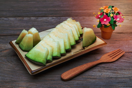 melon sliced on dish with wooden fork on wooden tableの写真素材