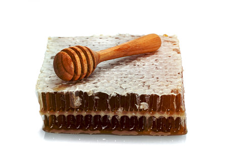 Fresh Honeycomb slice and wooden honey dipper isolated on white backgroundの写真素材