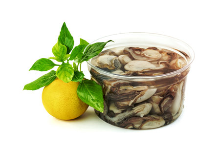 Oysters in plastic bowl with lemon and  leaf basil isolated on a white backgroundの写真素材