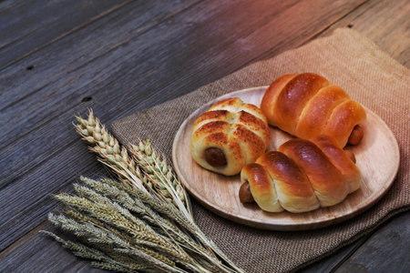 Sausage bread and wheat ears and sack on wooden background.の写真素材