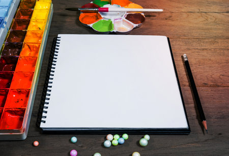 closeup open note book with tray colors on wood backgroundの写真素材