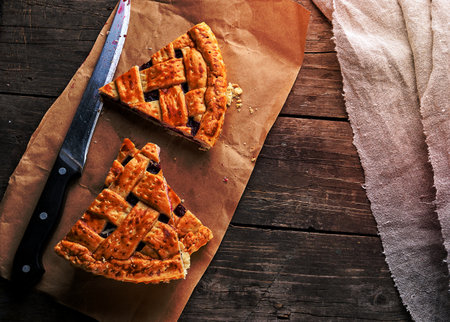 baked cakes with a cherry and a kitchen knife are on brown paper, wooden table, top viewの写真素材