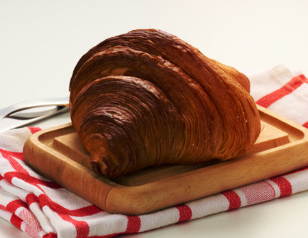Baked crisp croissant on wooden board, white table. Breakfastの写真素材