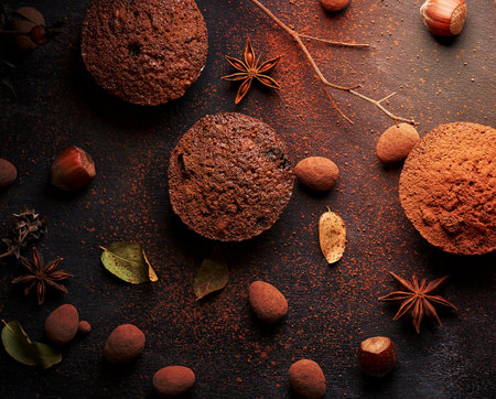 baked chocolate round muffins on a black background, pastries sprinkled with cocoa, top viewの写真素材