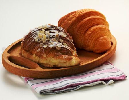 Baked crisp croissant on wooden board, white table. Breakfastの写真素材