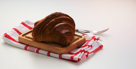 Baked crisp croissant on wooden board, white table. Breakfastの写真素材