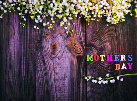 bouquet of fresh lilies of the valley on a gray wooden surface, next to the mother's day inscription, an empty space on the leftの写真素材