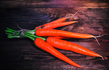 Fresh carrots tied with a rope in a bunch on a brown wooden backgroundの写真素材