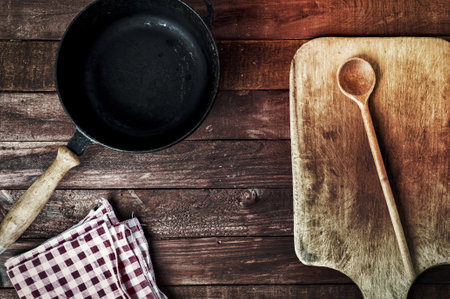 empty black metal pan and cutting board on a wooden surface, top viewの写真素材