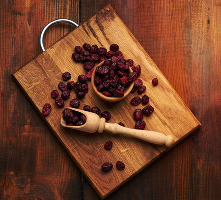 bunch of dried cranberries in a wooden spoon on a brown table. Delicious berry, top viewの写真素材