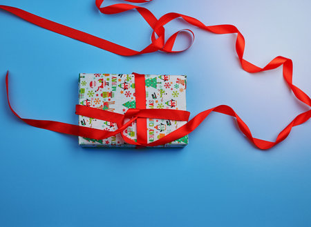gift wrapped in multi-colored paper on a blue background, festive backdrop, top viewの写真素材