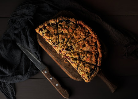 half plum pie crumble on a brown wooden cutting board, top viewの写真素材