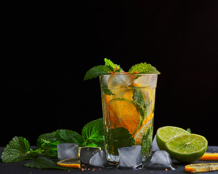 refreshing drink lemonade with lemons, mint leaves, ice cubes and lime in a glass on a black background, copy spaceの写真素材