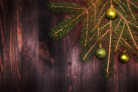 Green spruce branch with green Christmas toys in the corner of a brown board, top viewの写真素材