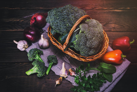 fresh cabbage broccoli in a basket on a brown wooden table, top view, vintage toningの写真素材