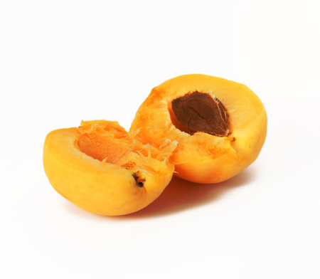 ripe yellow apricot broken in half on white backgroundの写真素材