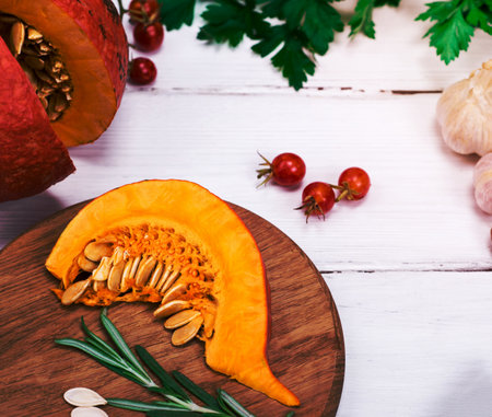 fresh slices of pumpkin and garlic with spices on a white wooden backgroundの写真素材