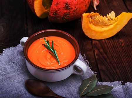 fresh pumpkin soup in a ceramic plate, on a brown wooden tableの写真素材