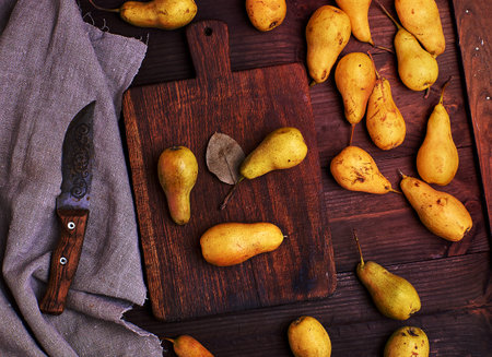 ripe yellow pears scattered on a brown wooden table, top viewの写真素材