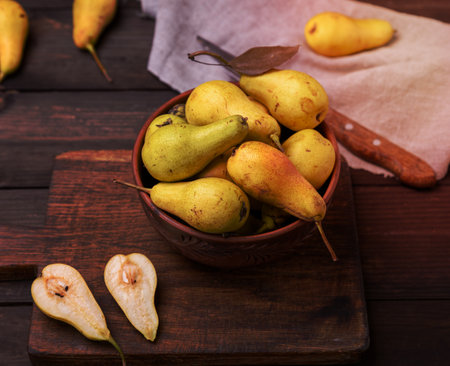 fresh ripe green pears in a brown clay bowl on a table, top viewの写真素材
