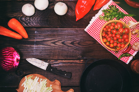 fresh ripe vegetables: tomatoes, onions, carrots and cabbage on a brown background, empty space in the middleの写真素材