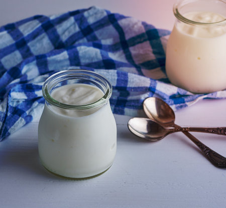 glass jars with homemade yogurt on a white wooden board,  top viewの写真素材