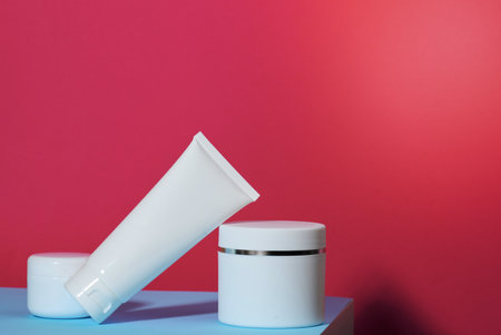 jar and empty white plastic tubes for cosmetics on a pink background. Packaging for cream, gel, serum, advertising and product promotion, mock upの写真素材