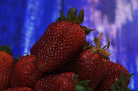 lots of ripe red strawberries on blue blurred background, close-upの写真素材