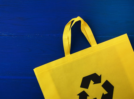 Reusable yellow viscose bag on blue wooden background, plastic waste reduction conceptの写真素材