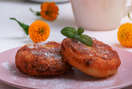 round roasted cottage cheese roasted in a pink ceramic plate on a white table, close upの写真素材