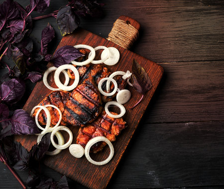 juicy grilled pork steaks on a brown wooden board, meat sprinkled with fresh onions, top viewの写真素材