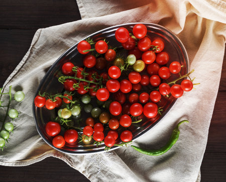 ripe red cherry tomatoes on an iron plate, top viewの写真素材