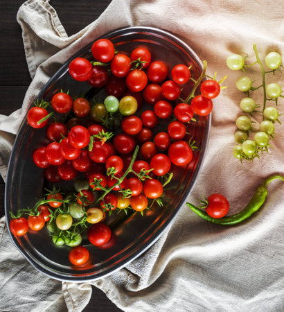 ripe red cherry tomatoes lie in a metal plate, top viewの写真素材