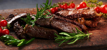 roasted piece of beef ribeye cut into pieces on a vintage brown chopping board. Well done. Appetizing steakの写真素材