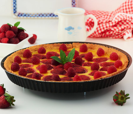 Round quiche with red strawberries and raspberries on a white tableの写真素材
