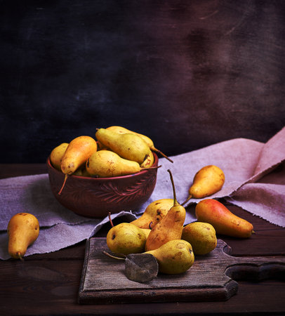 ripe yellow  pears in a brown clay bowl on a table,  close upの写真素材