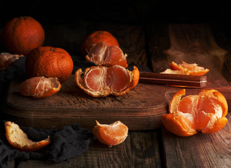ripe round tangerines and cut in half on an old vintage cutting board. Healthy vegetarian food. Citrus fruitの写真素材