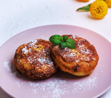 round roasted cottage cheese in a pink ceramic plate on a white table, close upの写真素材