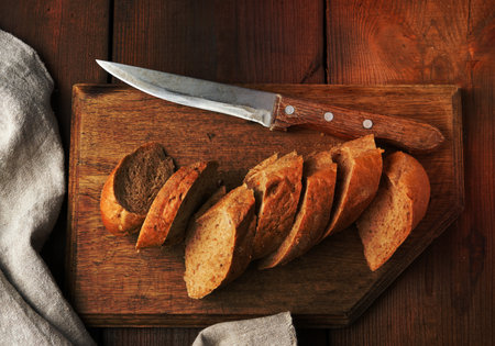 sliced rye flour baguette on a wooden cutting board, top viewの写真素材