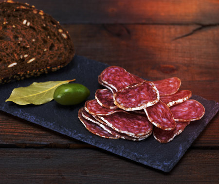 sliced smoked salami sausages and pieces of rye breadの写真素材