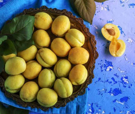 ripe apricot varieties of pineapple in a copper plate on a blue background, top viewの写真素材