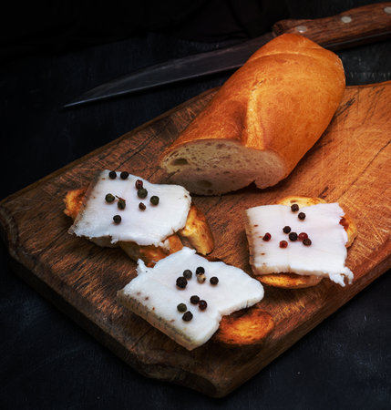 Sandwiches with slices of lard and with pepper on a brown wooden boardの写真素材